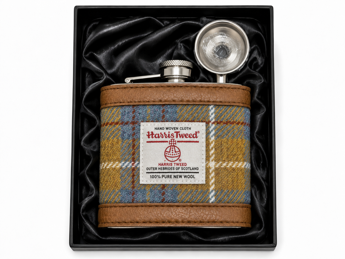 A Harris Tweed insulated flask with a brown leatherette border and a blue, yellow, and brown plaid pattern, presented in a black gift box with black satin lining. The flask has a silver metal cap and a white brand label.