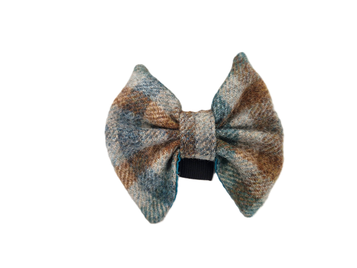 A small fabric bow accessory with a textured plaid pattern in muted blue, brown, and beige tones, secured with a black elastic band, shown against a plain white background.