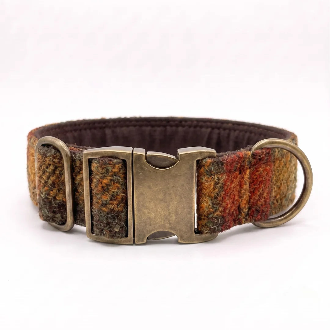 A woven tweed dog collar with a multicolor pattern of brown, yellow, and red, featuring an antique bronze buckle and metal rings, shown on a white background.