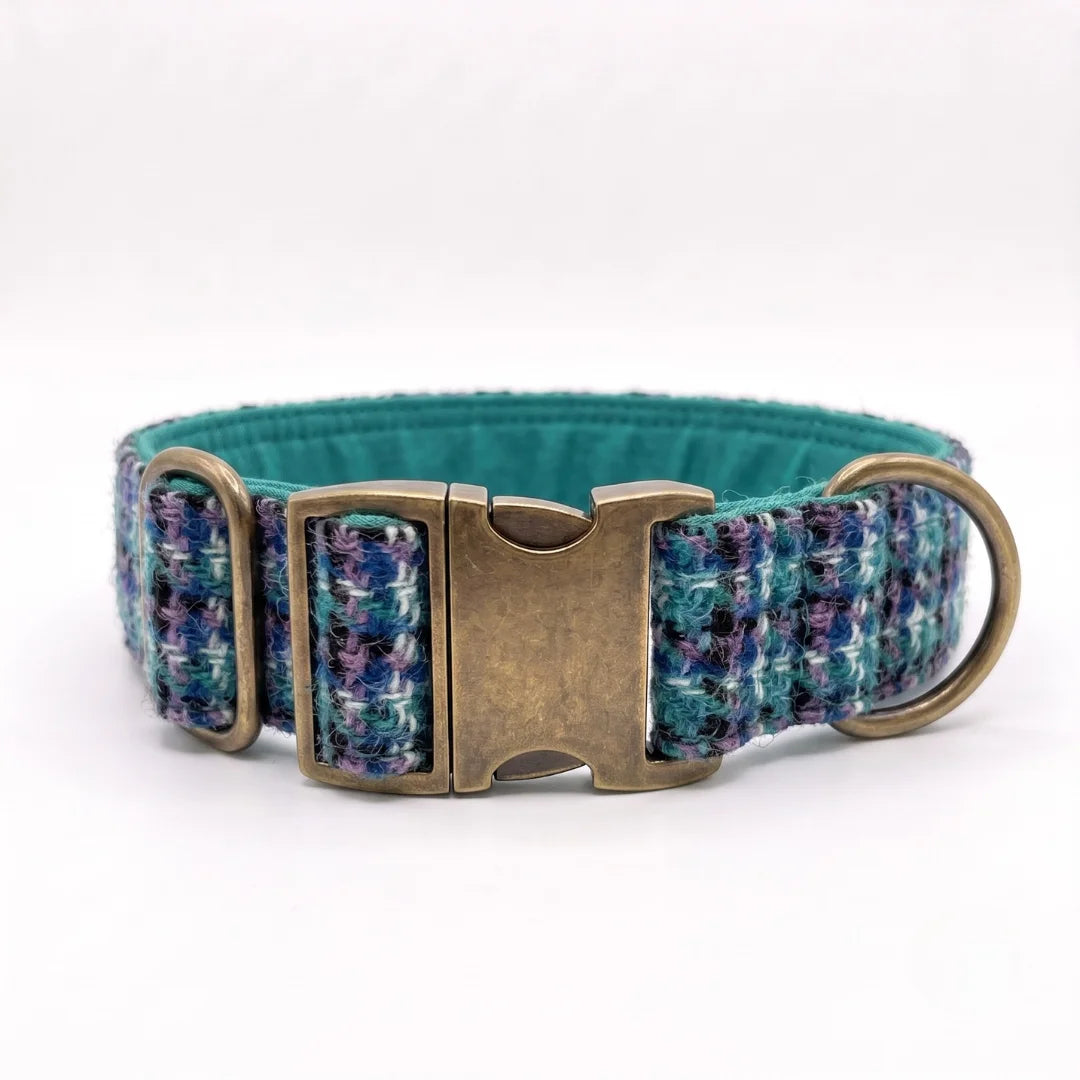 A harris tweed dog collar with a textured pattern of teal, blue, and purple threads, featuring an antique bronze buckle and a matching metal ring, shown on a white background.