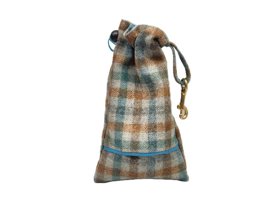 A small drawstring pouch made of plaid wool fabric in brown, beige, and teal tones, with a blue trim detail and a gold-tone metal clip on a white background.