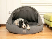 Black and white dog resting inside the grey cocoon bed with soft teddy fleece interior