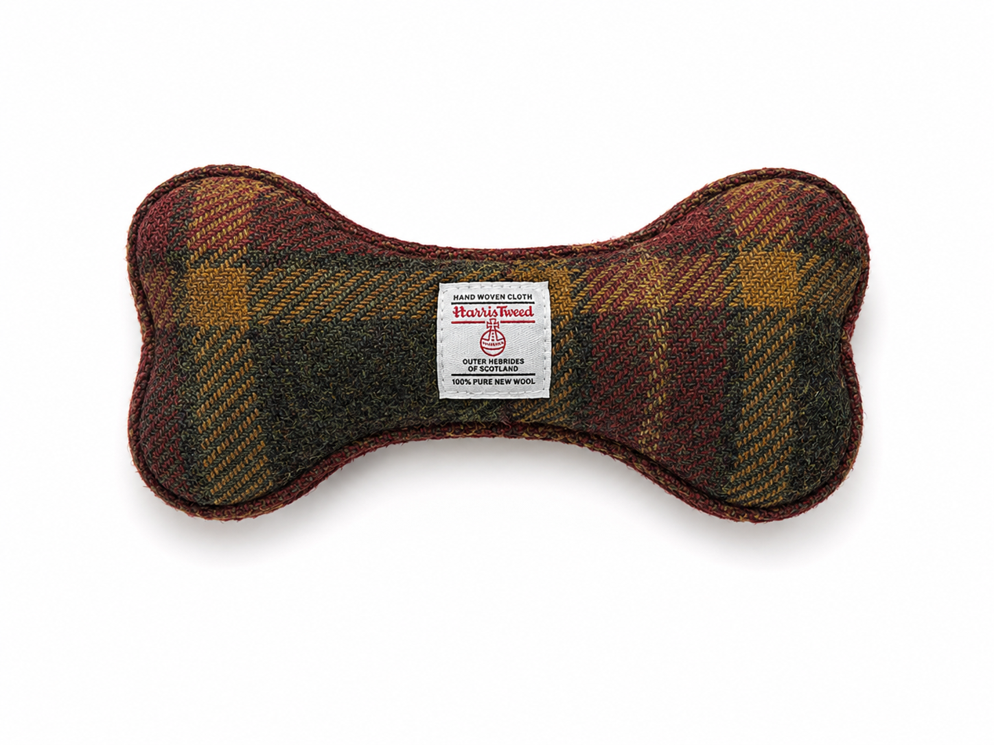A bone-shaped dog toy made of Harris Tweed wool, featuring a brown, red, and gold plaid pattern, with a white brand label in the center, set against a plain white background.
