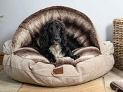 Black spaniel relaxing in beige dog cave bed with matching blanket - Collared Creatures