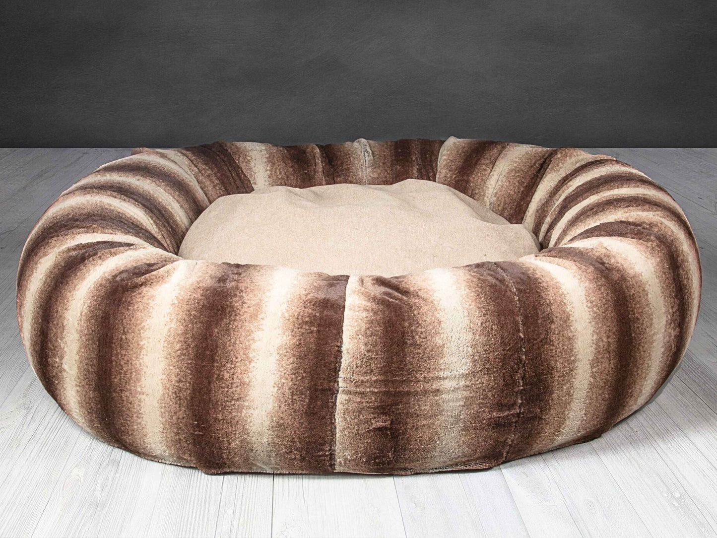 Empty luxury brown faux fur donut dog bed on light wooden flooring