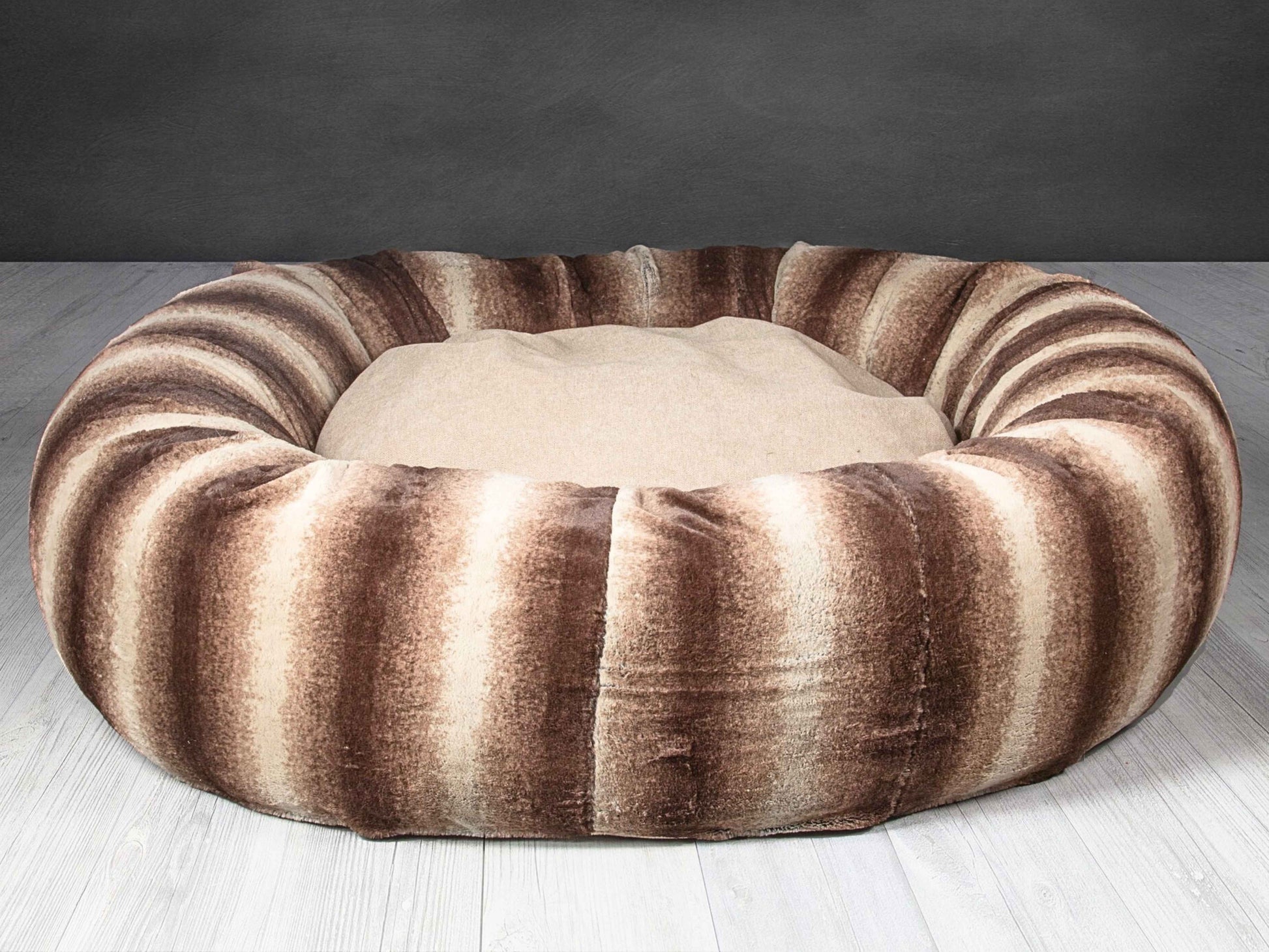 Empty luxury brown faux fur donut dog bed on light wooden flooring