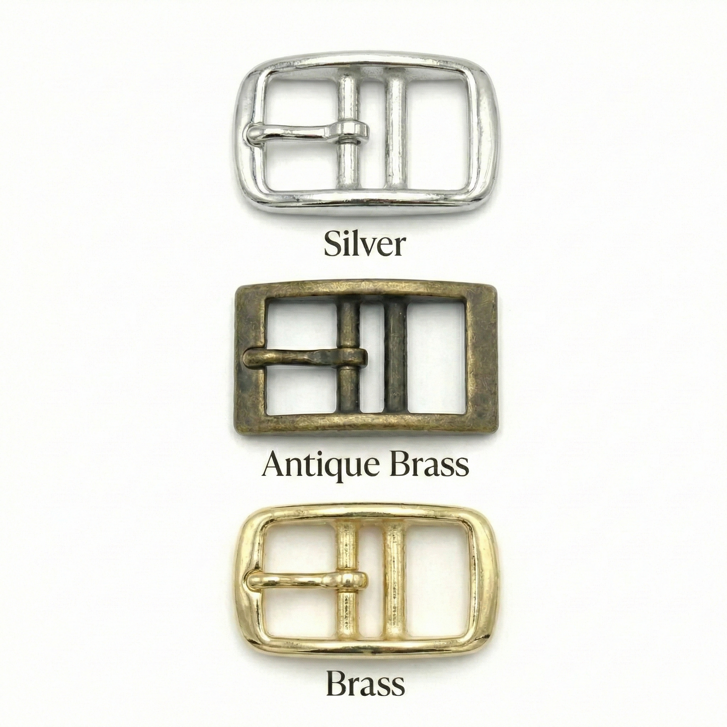 Three belt buckles in silver, antique brass, and brass on a white background