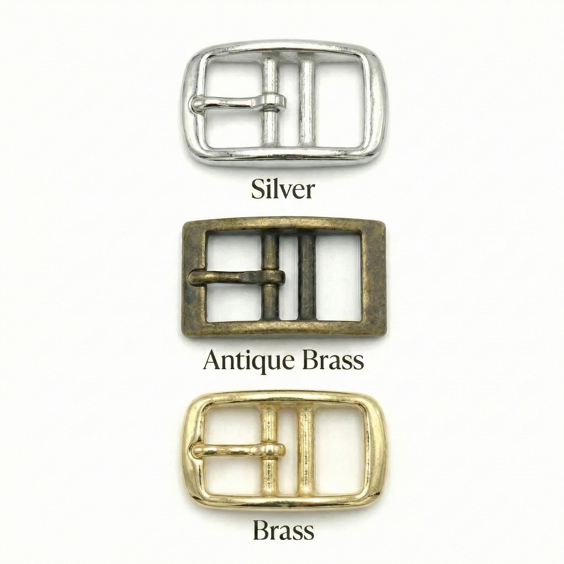 Three belt buckles in silver, antique brass, and brass on a white background