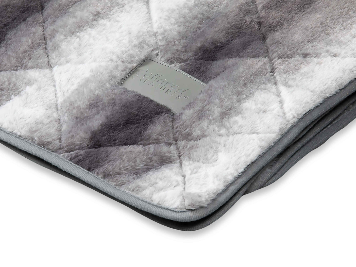 Close-up of luxury quilted grey faux fur dog blanket showing plush texture and stitching detail