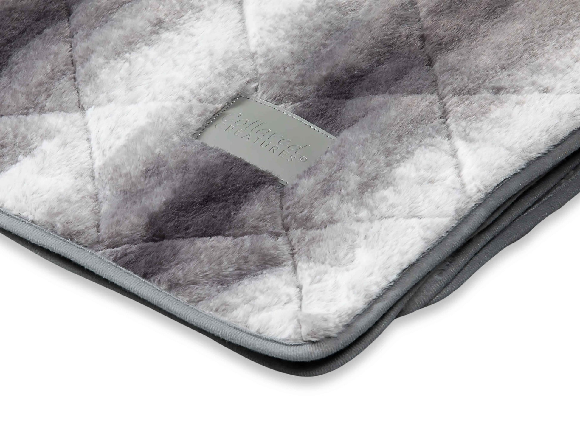 Close-up of luxury quilted grey faux fur dog blanket showing plush texture and stitching detail