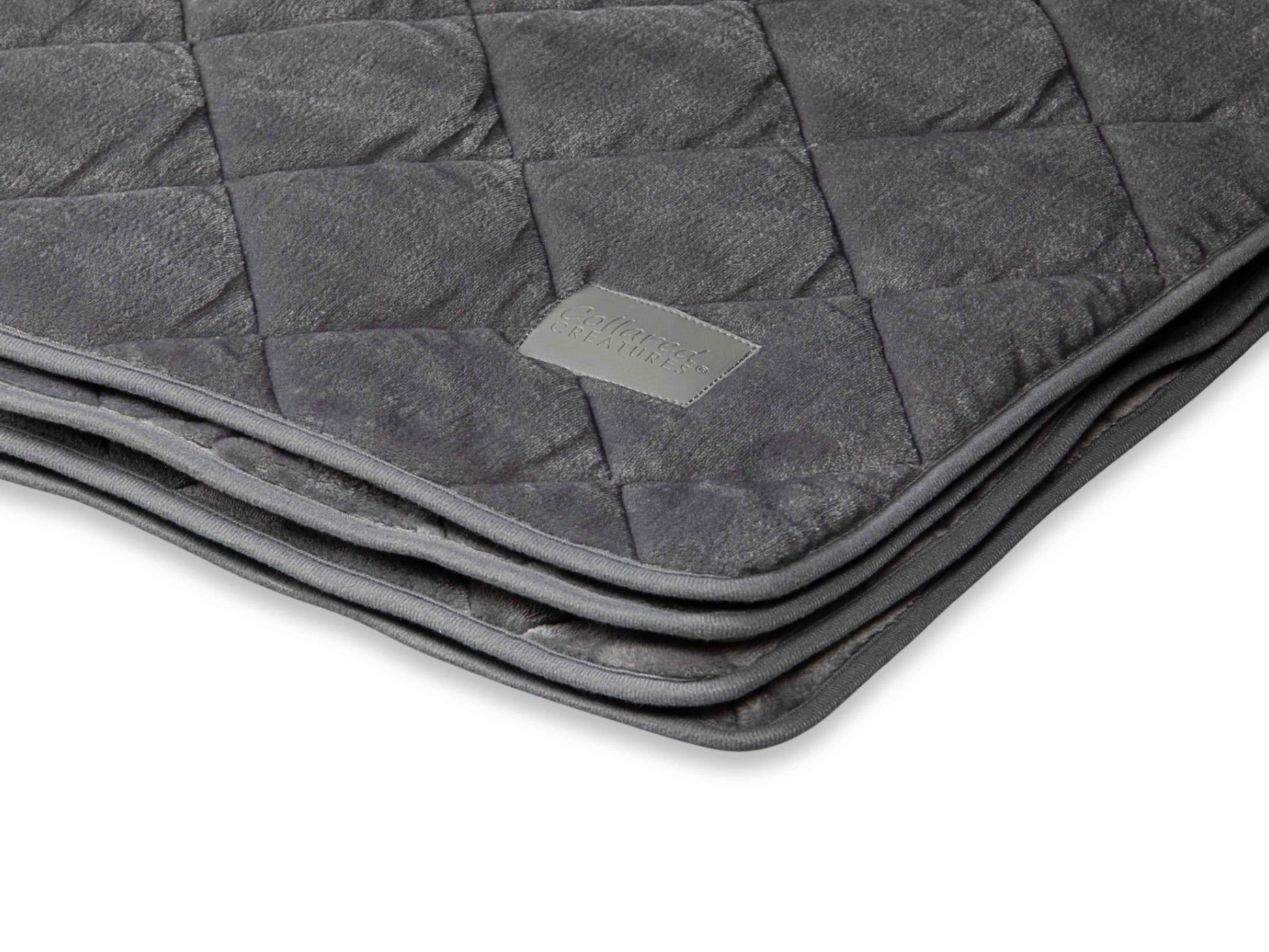 Close-up of quilted dog blanket in soft grey fabric showing texture and quality stitching.