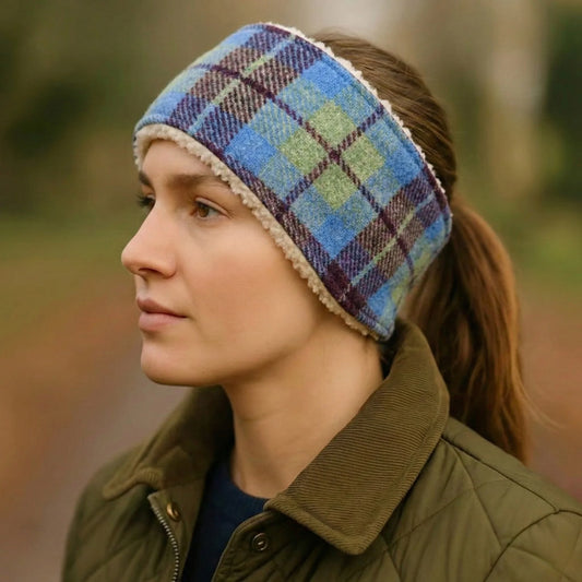 Person wearing a blue and burgundy tweed headband and green jacket outdoors