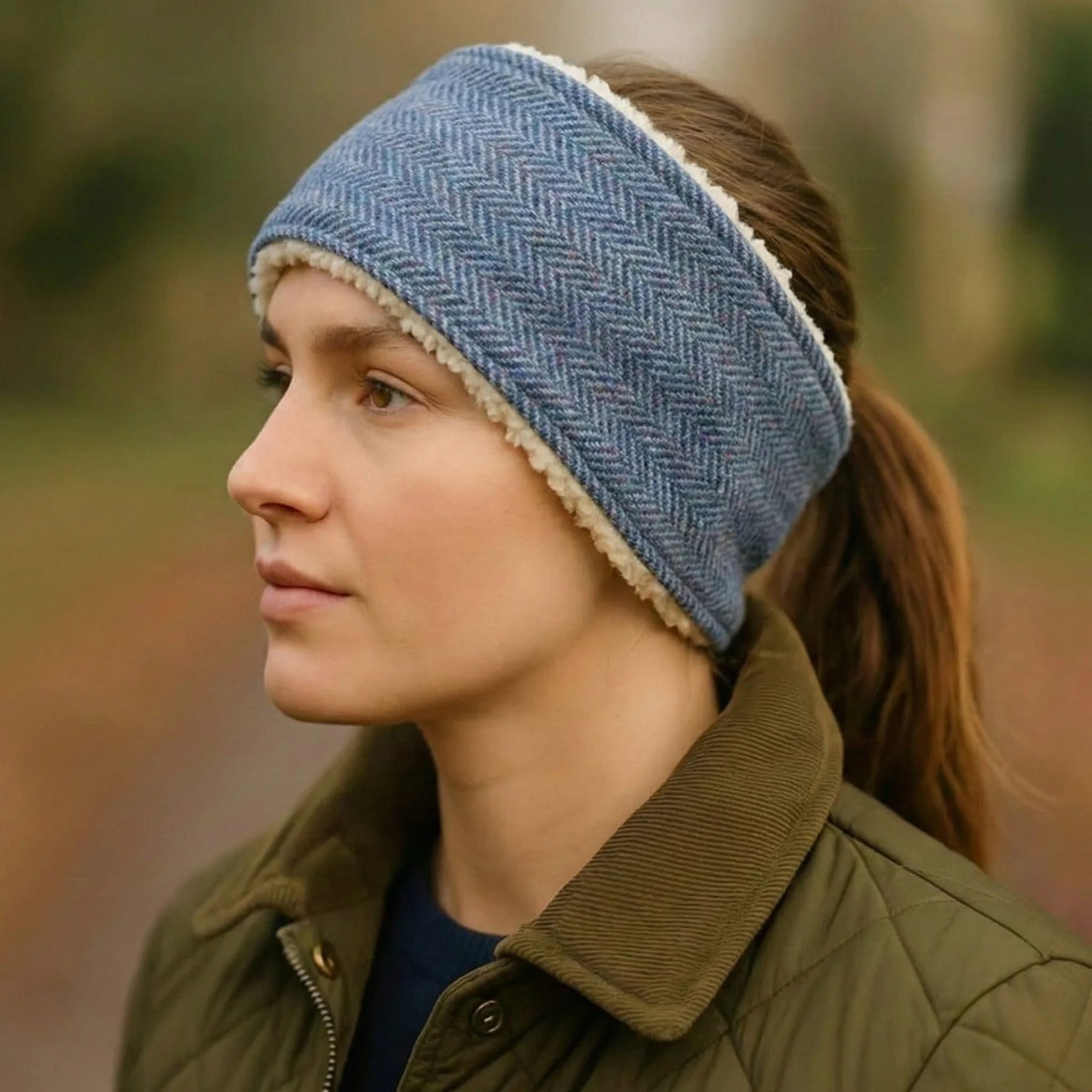 Woman wearing a blue herringbone tweed headband with a blurred natural background