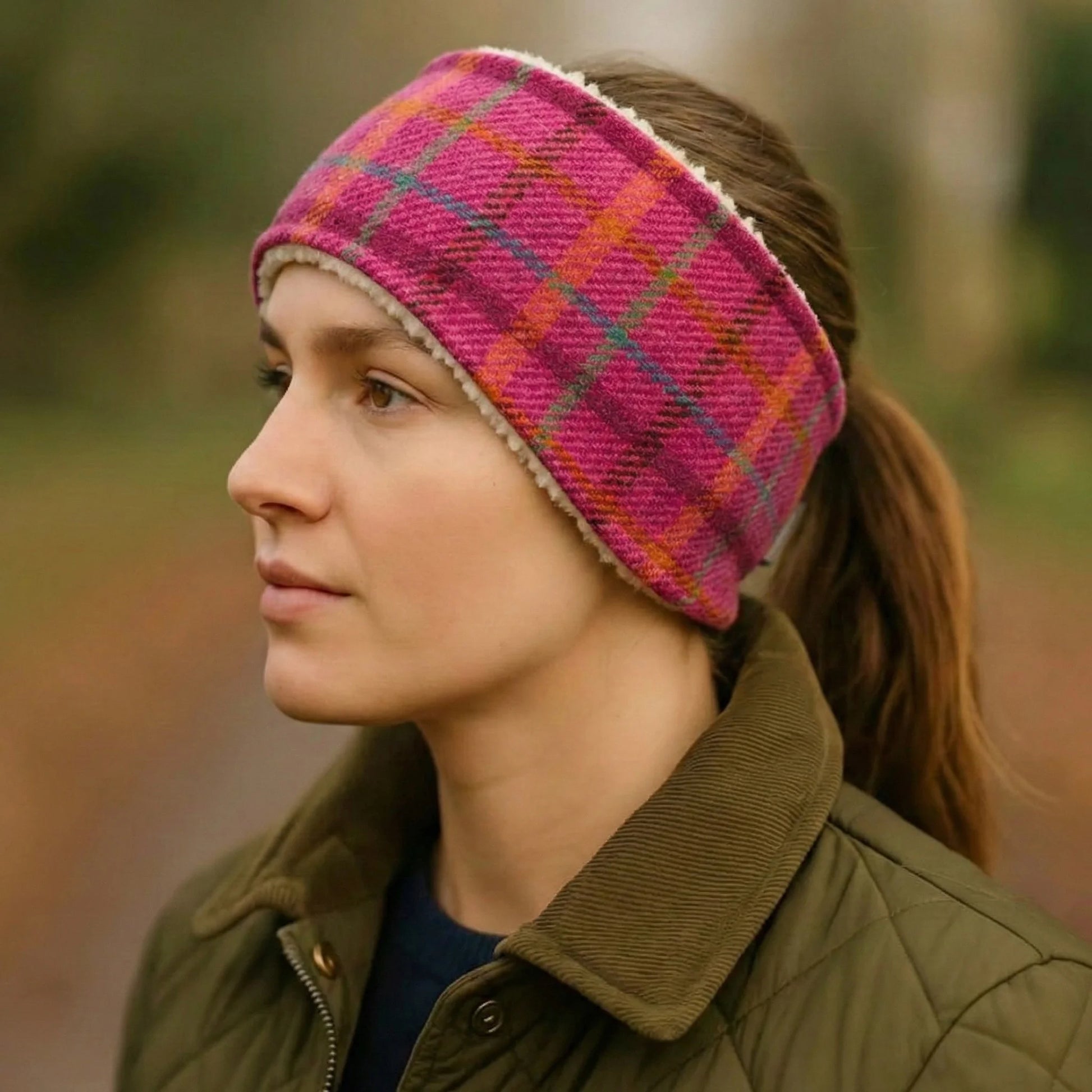 Woman wearing a pink plaid harris tweed headband with a blurred natural background