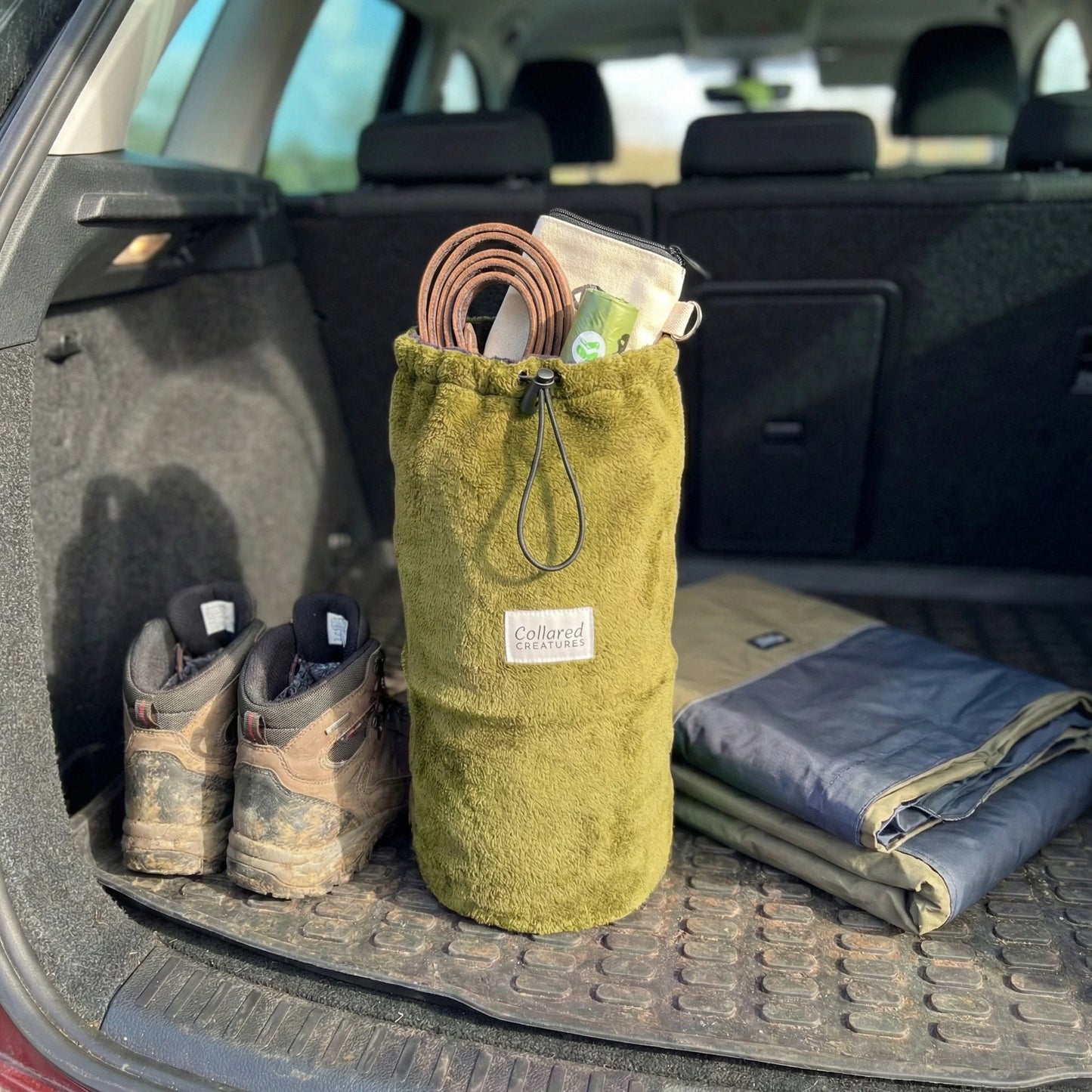 Green drawstring bag with walking gear in a car trunk