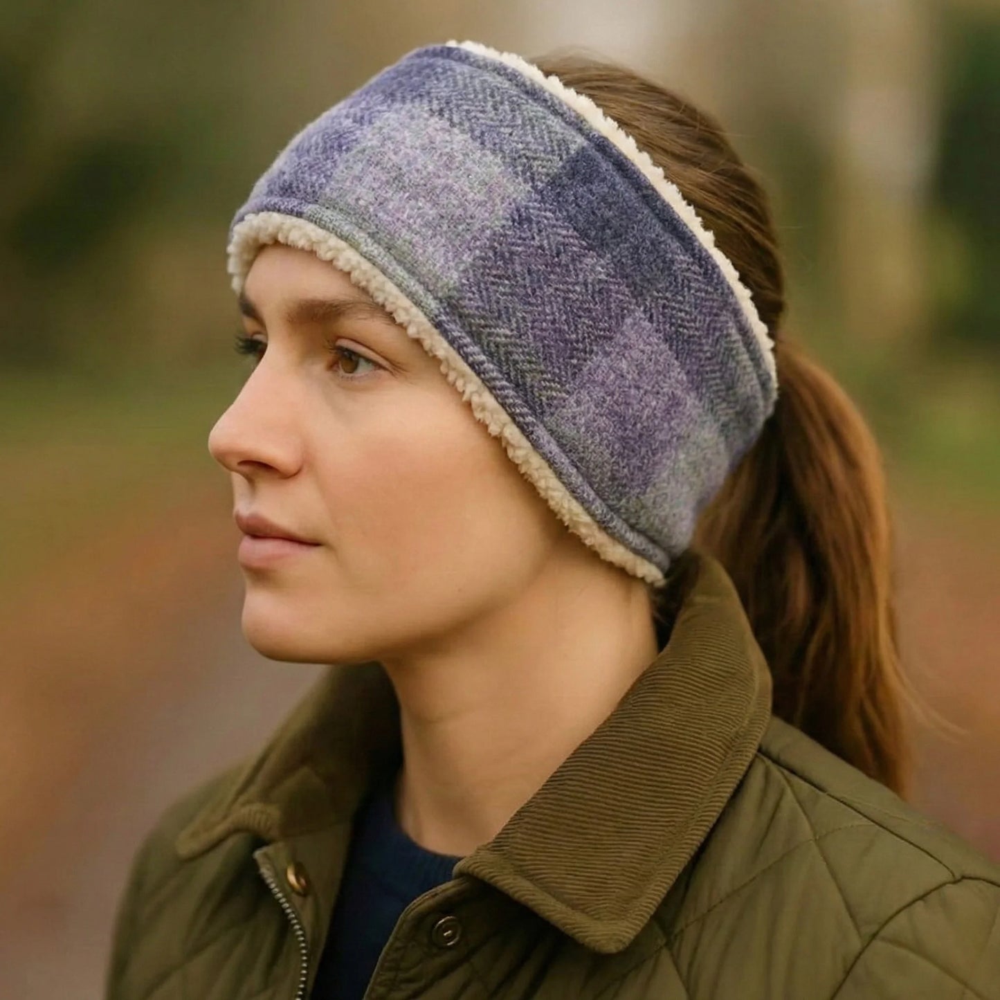 Woman wearing a purple check harris tweed headband and green jacket outdoors