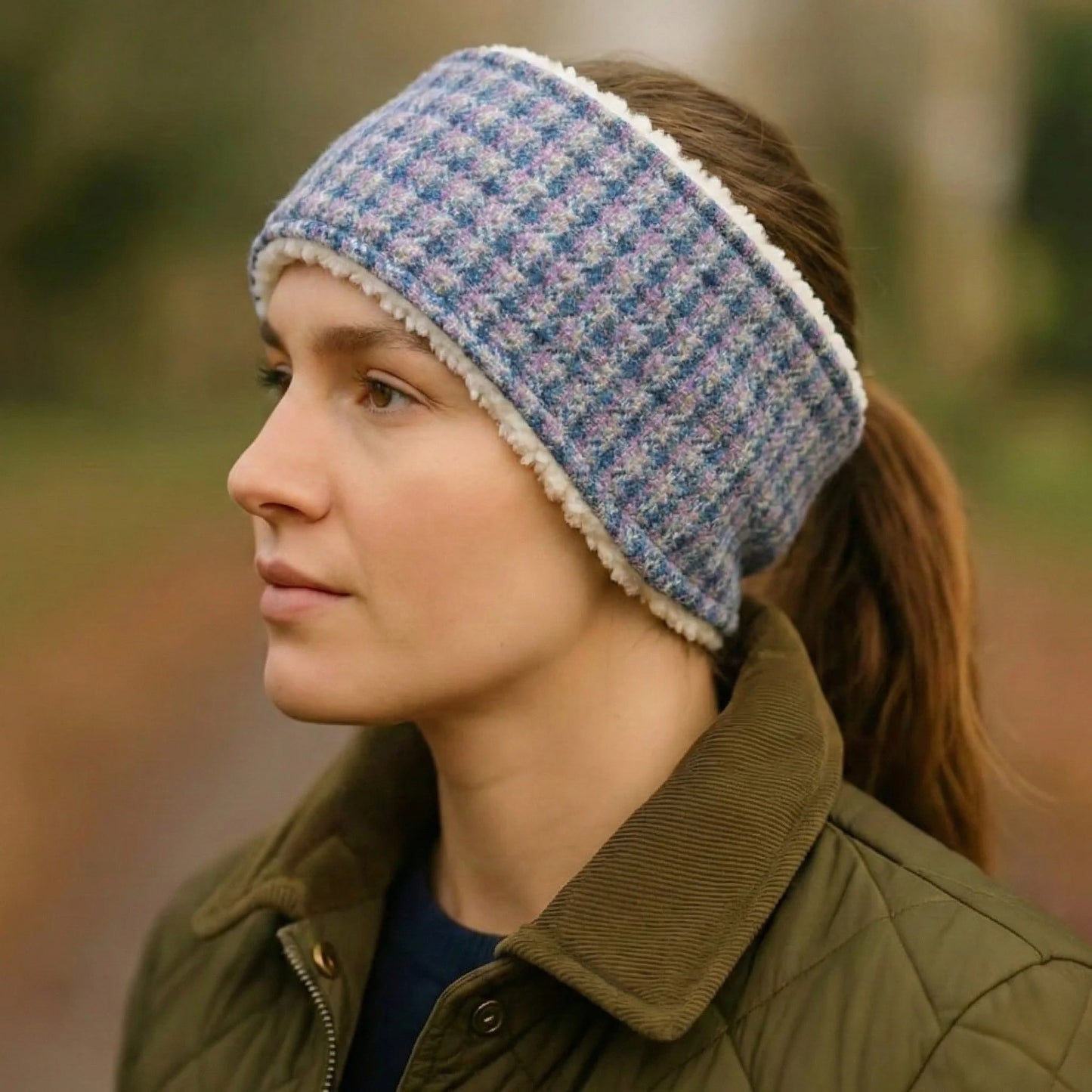 Person wearing a blue check tweed headband with a blurred natural background