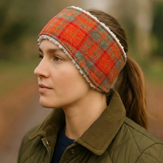Person wearing an orange and olive check tweed headband with a blurred natural background