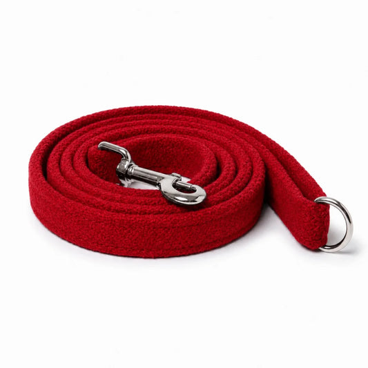 A red harris tweed textured dog leash coiled on a white background, featuring a silver metal snap hook and a silver D-ring.