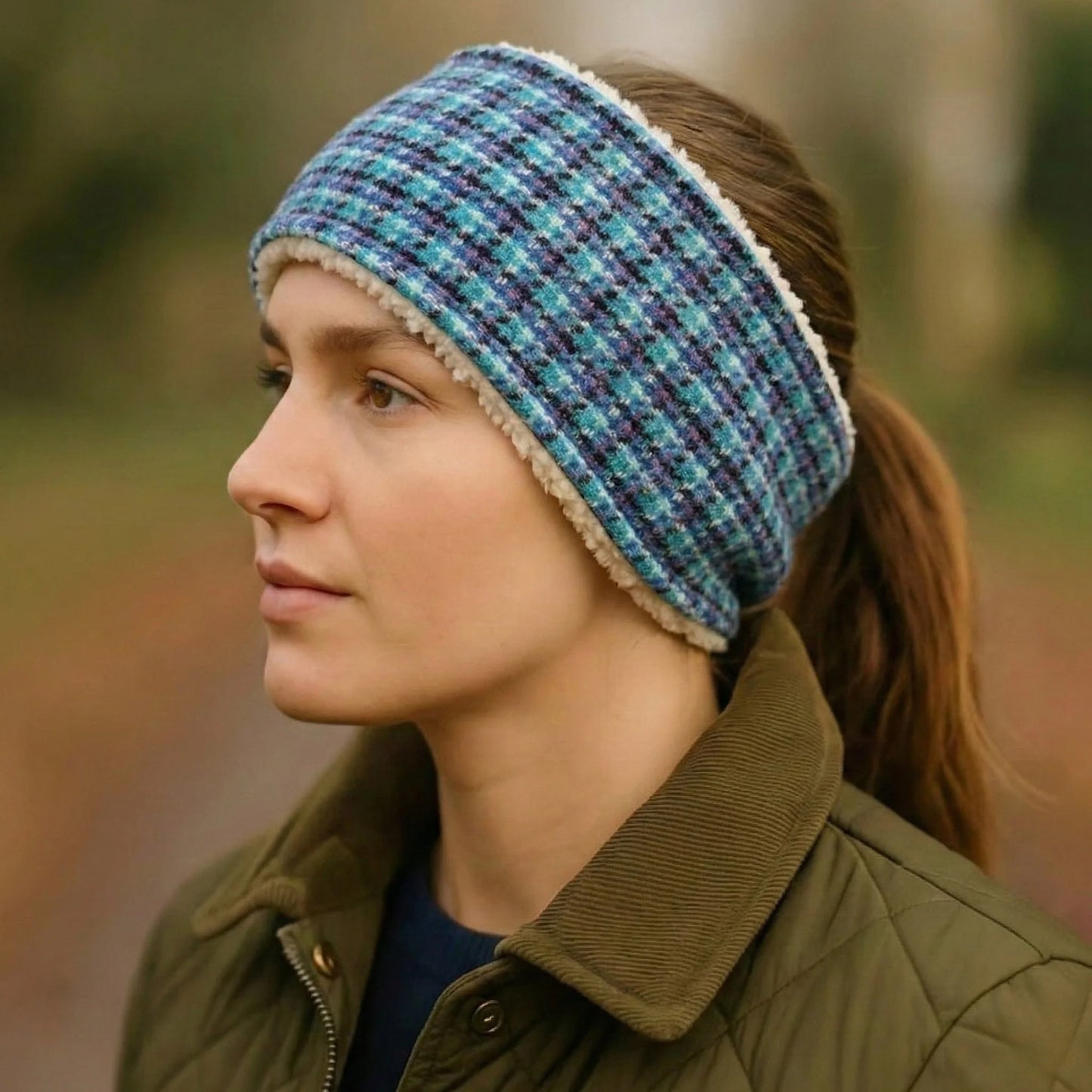 Woman wearing a blue plaid harris tweed headband with a blurred natural background