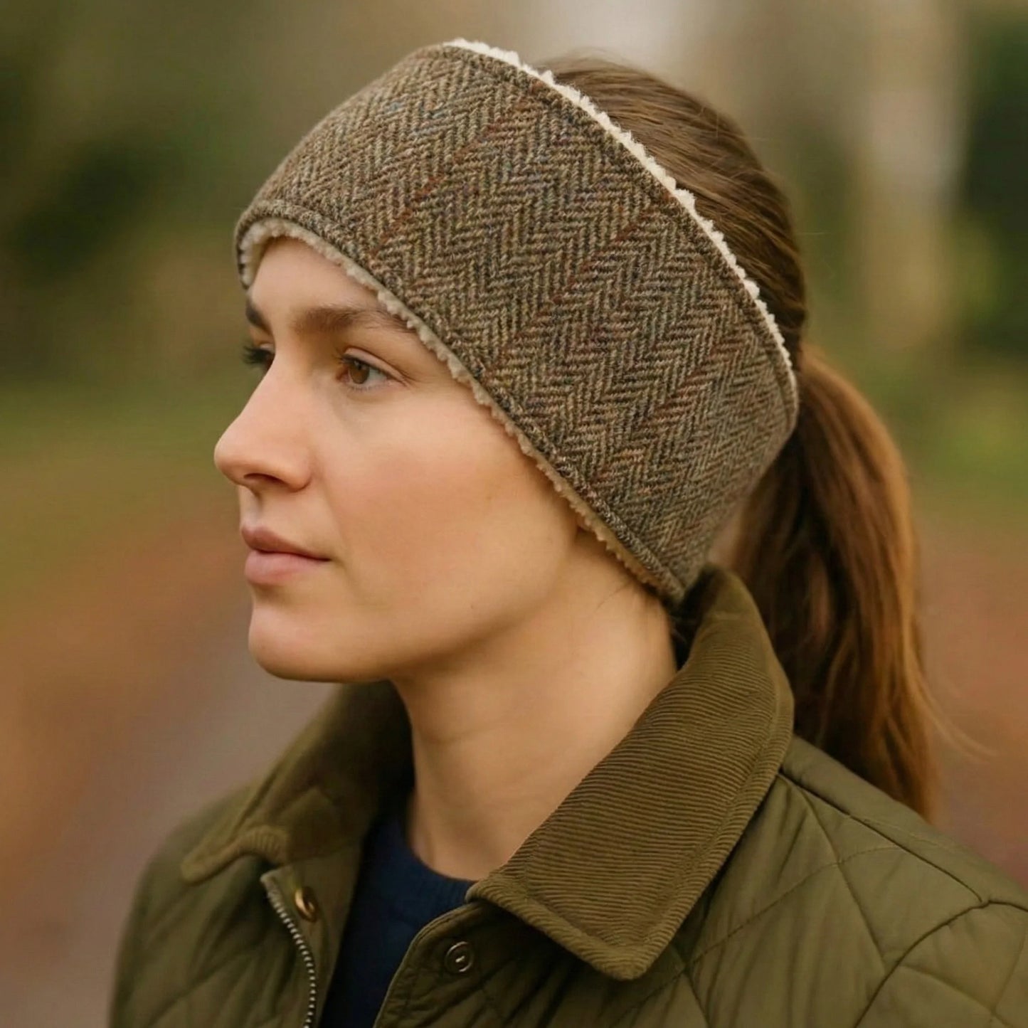 Woman wearing a herringbone patterned headband and green jacket outdoors