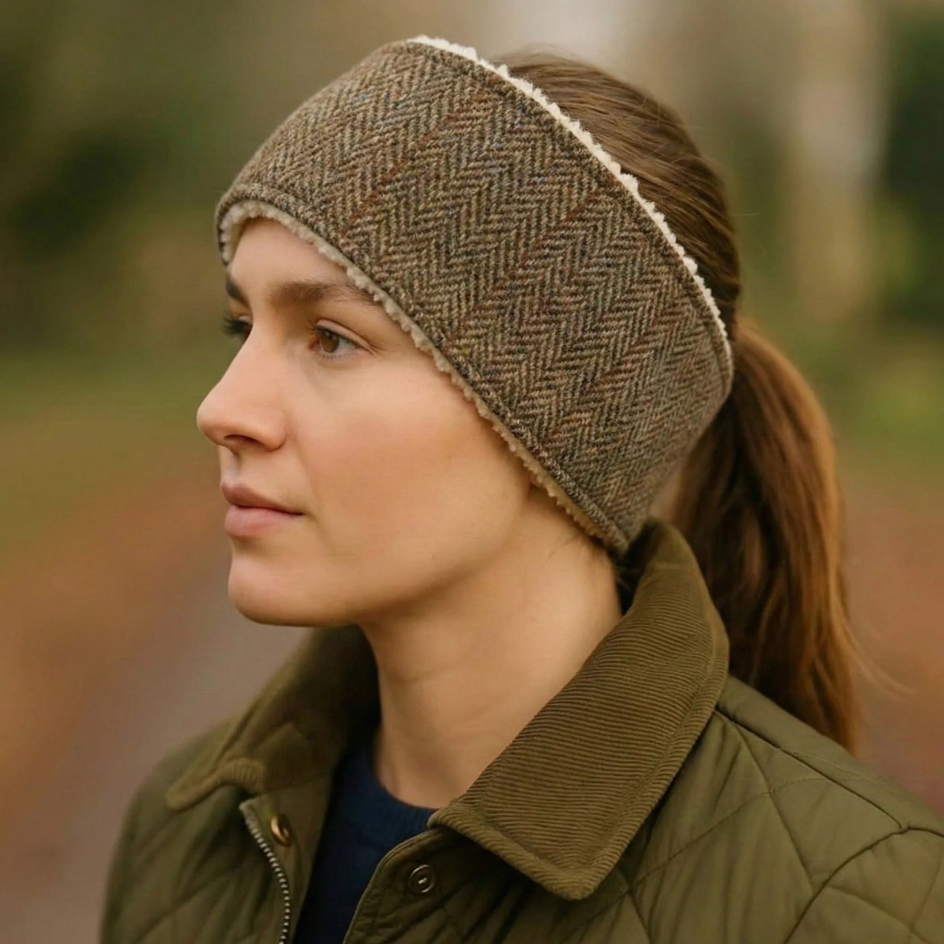 Woman wearing a herringbone patterned headband and green jacket outdoors