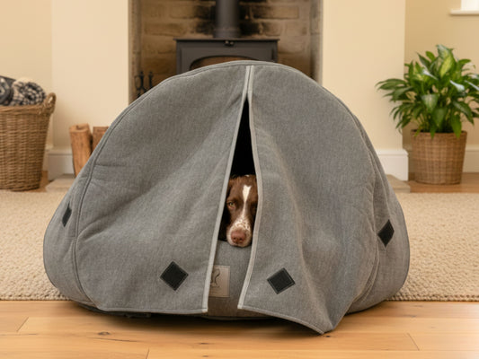 grey cocoon pet bed with a dog peeking out of curtains in a home setting