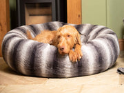 Large breed dog curled up in soft grey striped donut dog bed