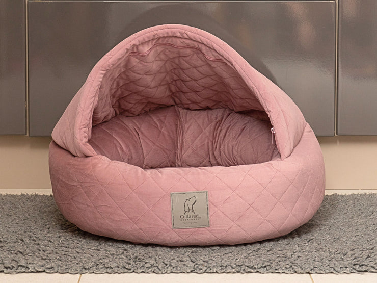 Studio photo of Dusky Pink Quilted Cocoon Dog Bed with structured hood and logo badge - Collared Creatures