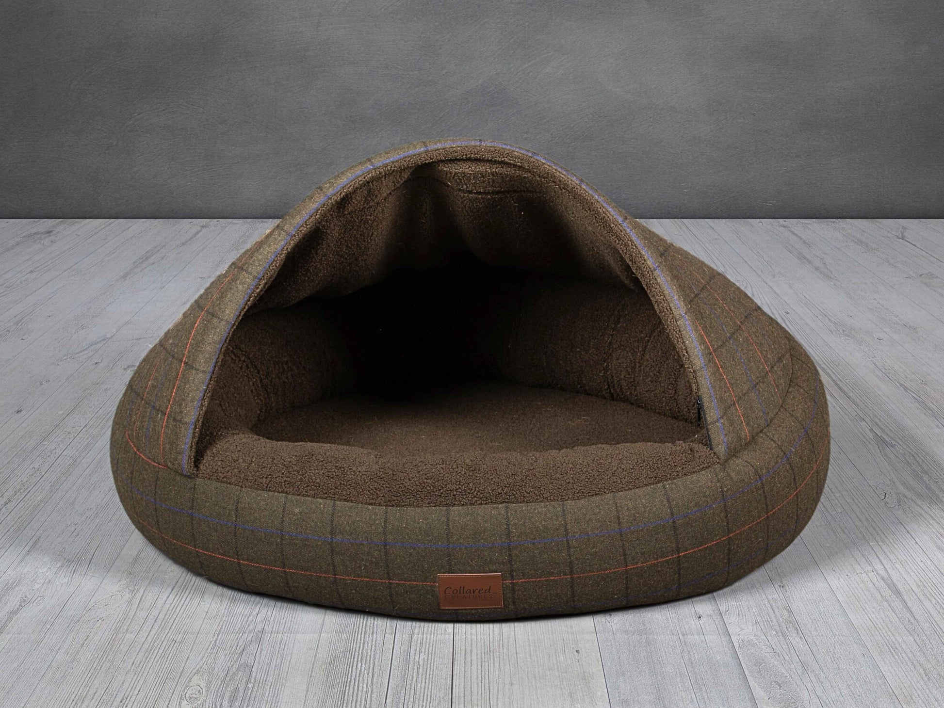 Empty Collared Creatures cocoon dog bed in green tweed on wood floor