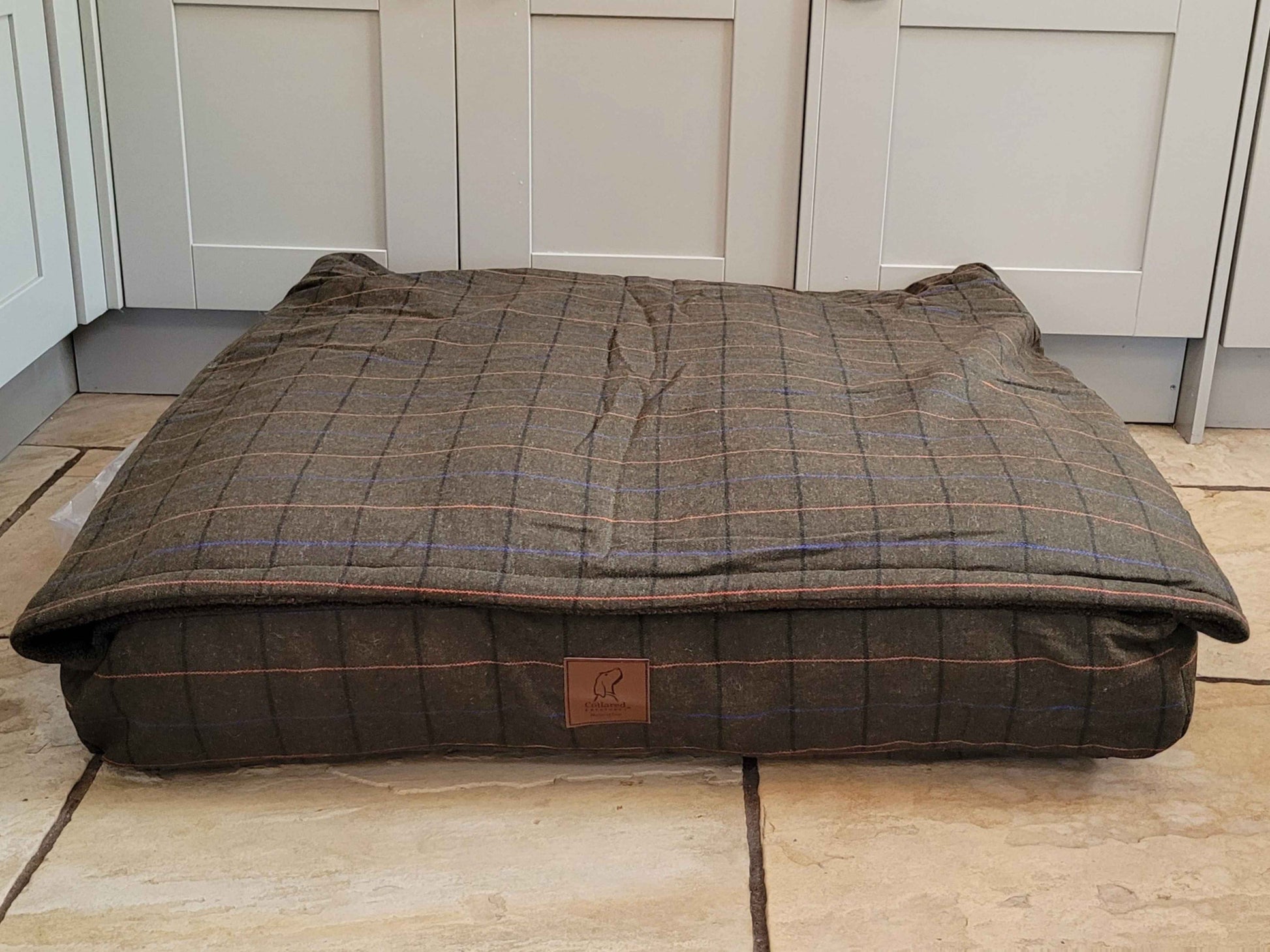 Green Tweed Dog Snuggle Bed neatly arranged in a modern kitchen