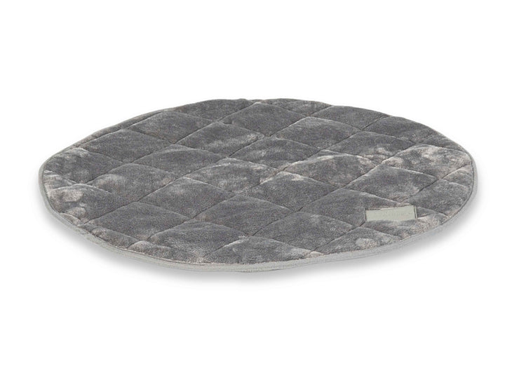 Angled view of grey quilted round dog mat with soft plush finish and piped edges