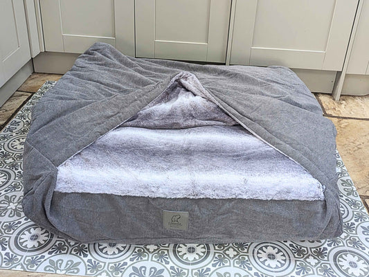 Grey dog snuggle sack bed with open hood showing soft faux fur interior - Collared Creatures