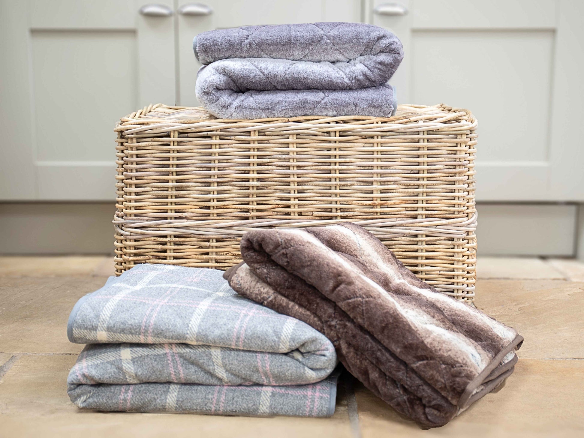 Stacked luxury grey faux fur dog blankets in a range of patterns and finishes