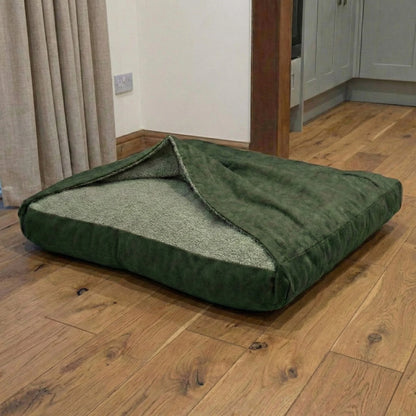 Green hooded dog bed on a wooden floor in a room with curtains and a door.