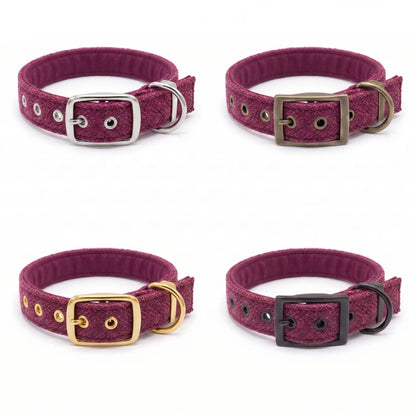 Four dog collars in a deep magenta-purple textured fabric, arranged in a 2x2 grid on a white background. Each collar features a different metal buckle and D-ring combination: silver, antique bronze, gold, and black.