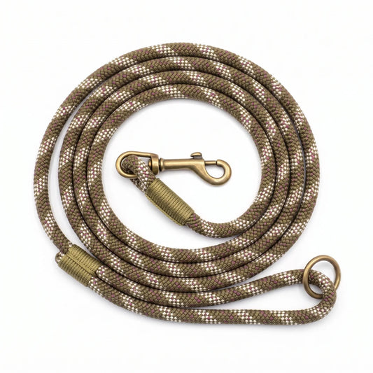 A coiled dog leash made of braided rope in a brown and beige camouflage pattern, with antique bronze metal hardware including a snap hook, wrap, and ring, shown on a plain white background.