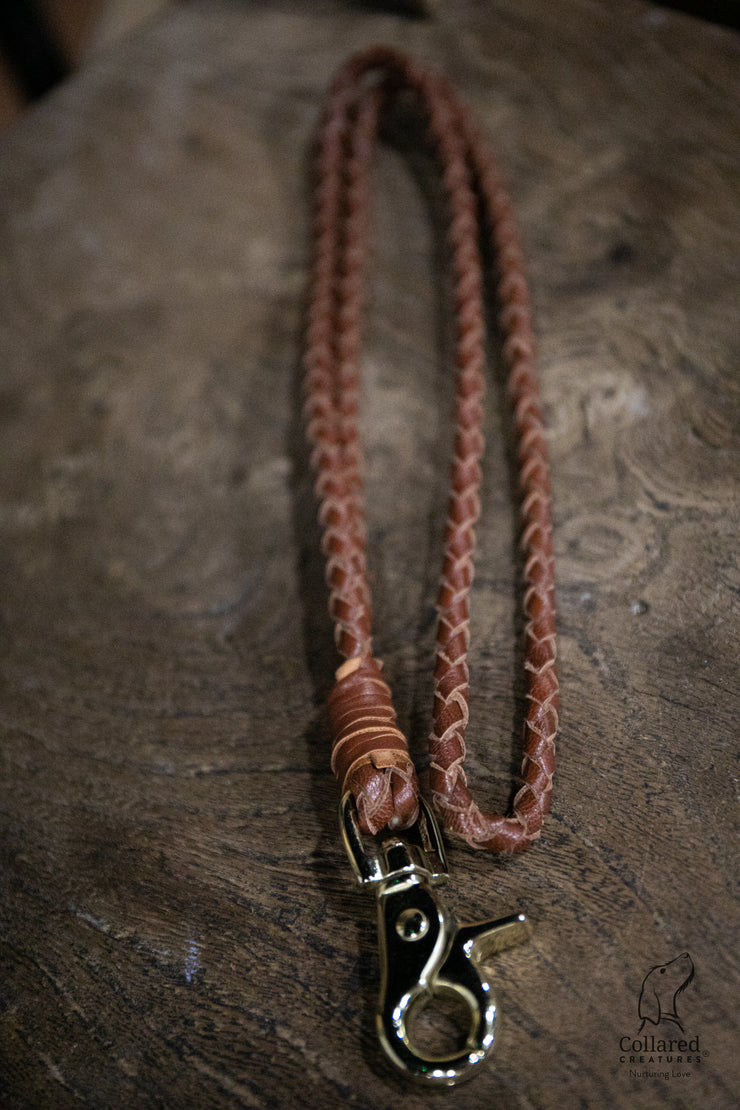 rich tan braided leather lanyard by Collared Creatures sat on a dark wooded block