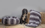 lack and white Spaniel standing at the side of a Collared Creatures luxury grey faux fur donut dog bed with matching luxury grey faux fur dog blanket - sofa throw at the side